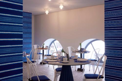 a dining room with tables and chairs and windows at Fresh Hotel, a member of Design Hotels in Athens