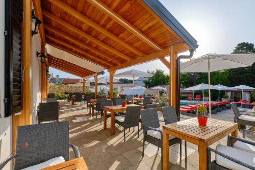 a patio with tables and chairs and umbrellas at Dolphin Suites in Veli Lošinj