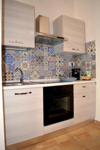 a kitchen with white cabinets and a black oven at Verderame - Apartment in Licusati