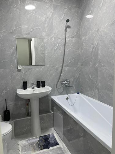 uma casa de banho com um lavatório, uma banheira e um WC. em Sholpan city studia 118/2 em Almaty
