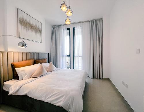 a bedroom with a large bed with white sheets at Green community - Tennis, streetball - 15 mins sea in Dubai