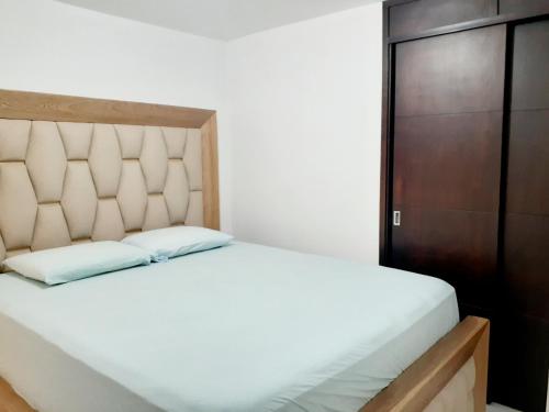 a bedroom with a white bed and a wooden cabinet at Apartamento centro MDE in Medellín