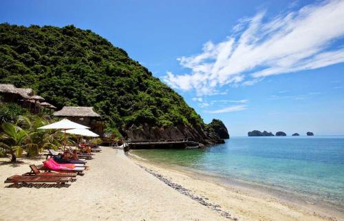 a beach with chairs and umbrellas and the ocean at PHÚC AN HOSTEL in Cat Ba