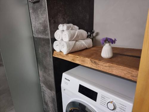 a pile of towels on a shelf above a washing machine at Chalet Grittelihus, large bathroom, Lots of living space, nahe Interlaken in Diemtigen