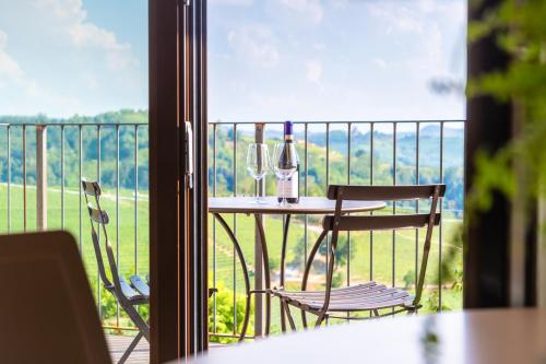 una mesa con 2 sillas y una botella de vino en el balcón en Il Cortile Suites, en Diano dʼAlba