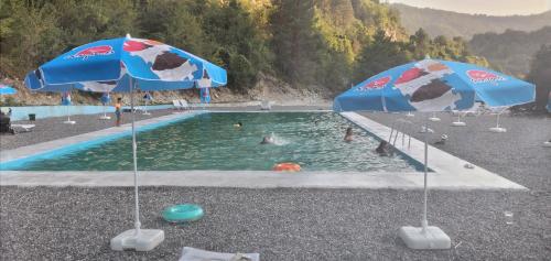 a pool with two umbrellas and people in the water at Panorama in Kutaisi