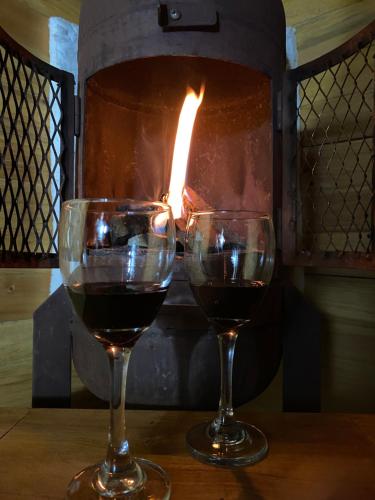 two glasses of wine sitting on a table in front of a fireplace at El Refugio del Santo in El Lindero