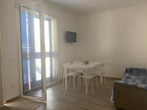- une table et des chaises blanches dans une chambre avec fenêtre dans l'établissement Gemma Mediterranea, à Campomarino