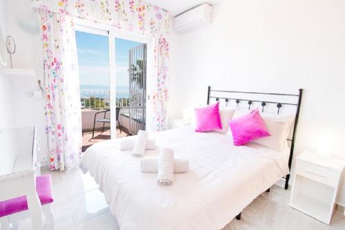 アロヨ・デ・ラ・ミエルにあるVilla Yolanda del Marの白いベッドルーム(ピンクの枕が付いた大型ベッド付)