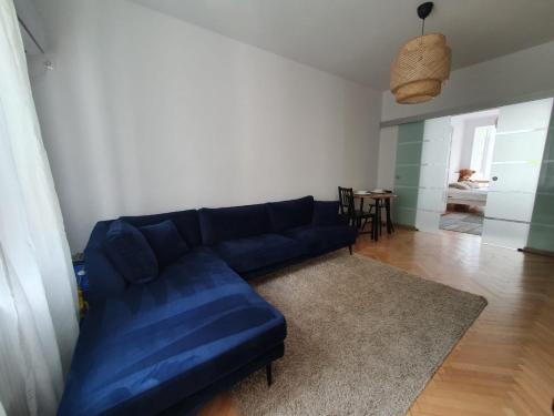 a blue couch in a living room with a table at Spacious and quiet 1BR apartment in Floreasca in Bucharest
