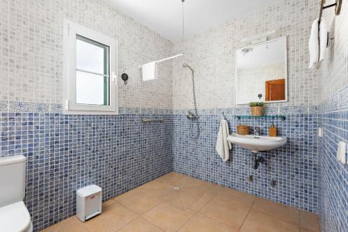 a blue tiled bathroom with a sink and a toilet at Villas Cala Galdana in Cala Galdana