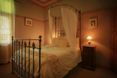 um quarto com uma cama de dossel com lençóis brancos em Freida - Historic Farmhouse Bellingen em Gleniffer