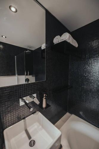a bathroom with a sink and a black tiled wall at Mansion Botánico Premium Buenos Aires in Buenos Aires