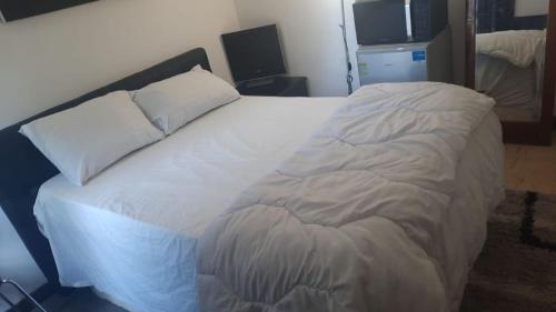 un grand lit blanc avec deux oreillers dessus dans l'établissement Colocation ROOMS, à Sarcelles