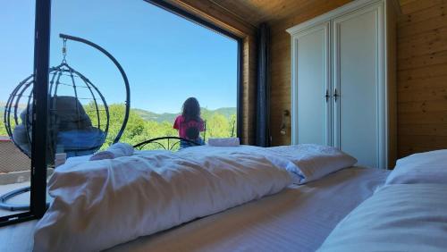 a woman standing in a room with a large window at Cabanele CARMEL in Muntele Rece