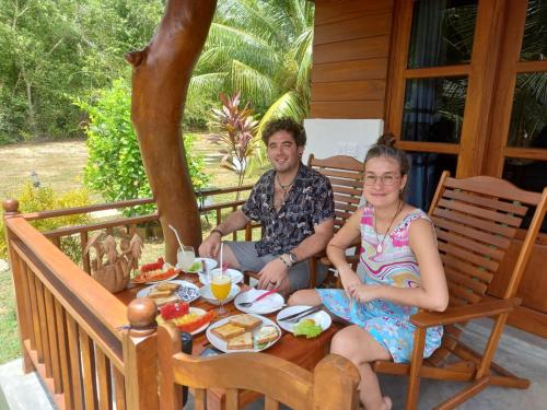坦加拉的住宿－Hanguk Lanka Lagoon Villa，坐在餐桌旁吃饭的男人和女人