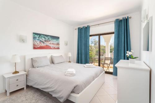 - une chambre blanche avec un lit et un balcon dans l'établissement Lively Charming Apartment w Pool, à Praia do Carvoeiro