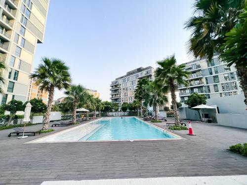a swimming pool with palm trees and buildings at Green community - Tennis, streetball - 15 mins sea in Dubai