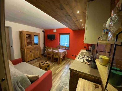 a kitchen with red walls and a living room at Appartamento sul Lago di Maen in Valtournenche