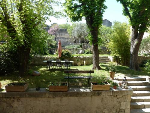 un parc avec un banc, des tables et des arbres dans l'établissement Le Palazzo d'Orgon - chambre d'hôtes dans les Alpilles, à Orgon