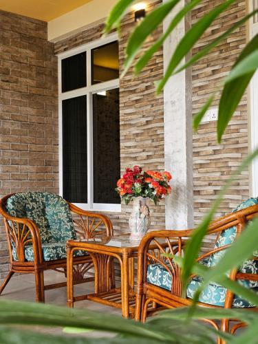 un patio con 2 sillas y una mesa con un jarrón de flores en White Sand Inn en Maamigili