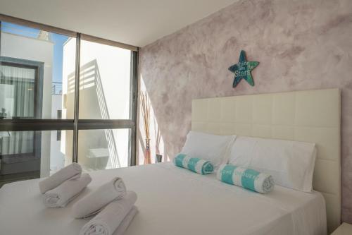 um quarto com uma cama branca e toalhas em Pink Waves House em El Médano