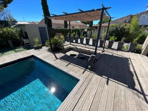 - une piscine sur une terrasse en bois avec un kiosque dans l'établissement Splendide villa avec piscine et salle cinéma, au Grau-dʼAgde