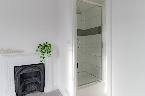 a bathroom with a fireplace and a glass shower at Fabulous, vibrant, town house, central Bath Road in Cheltenham