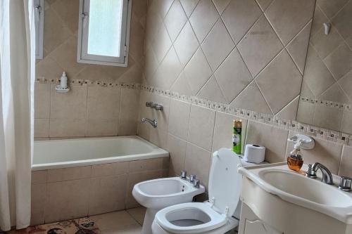 a bathroom with a toilet and a sink and a tub at CERCA DE TODO amplio in Mendoza