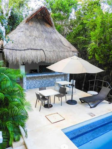 a patio with a table and umbrella next to a pool at Aku-Chic Newly furbished condo Jungle pool in Xetna