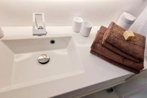 een witte wastafel met een handdoek en bekers bij Le rêve de Déborah in Cap d'Agde