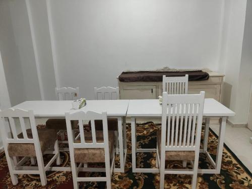 a white dining room table with four white chairs at happy home in Luxor
