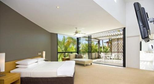 ヌーサヘッズにあるLuxury Retreat with Private Beach & Jettyのベッドルーム(ベッド1台、テレビ付)、パティオが備わります。