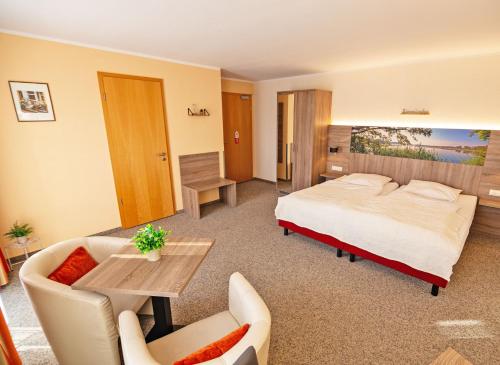 ヴァーレンにあるHotel Zur Sonneのベッド、テーブル、椅子が備わるホテルルームです。