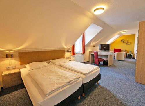 ein Schlafzimmer mit einem Bett und einem Schreibtisch in einem Zimmer in der Unterkunft Hotel Zur Sonne in Waren (Müritz)