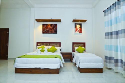 2 camas en una habitación con paredes blancas en Thinaya lake resort, en Anuradhapura