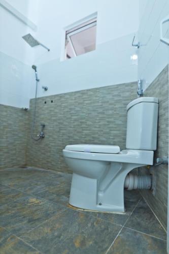 a white toilet in a bathroom with a shower at Thinaya Lake Resort in Anuradhapura