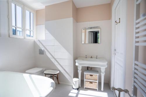 uma casa de banho branca com um lavatório e um WC em La Demeure du Tabellion em Le Mont-Dore