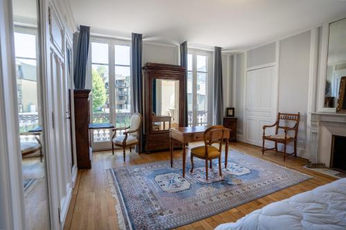 sala de estar con mesa, sillas y chimenea en La Demeure du Tabellion en Le Mont-Dore