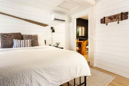 a white bedroom with a bed and a doorway at The Old Kettle Cabin with Hot Tub in Mill Village