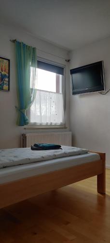 a bedroom with a bed with a television and a window at Pension Ramser in Lindhorst