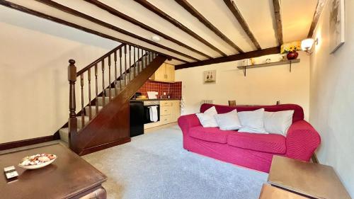 a living room with a red couch and a staircase at Curry Mallet Cottages in Taunton