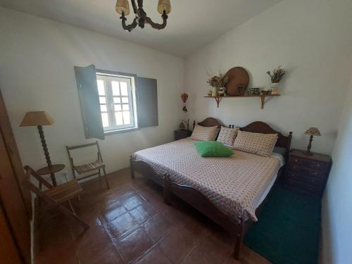 a bedroom with a bed and a window and a chair at Montinho do Palanque in Viana do Alentejo