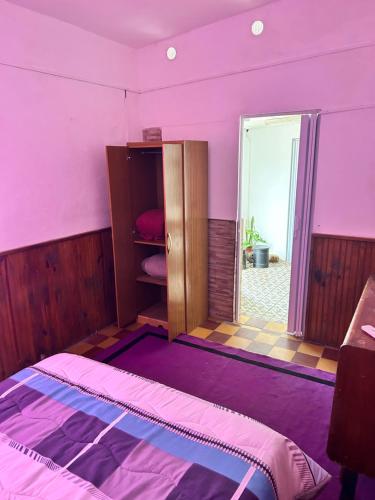 Habitación de color rosa con cama y ventana en APART PELUSA en Fray Bentos