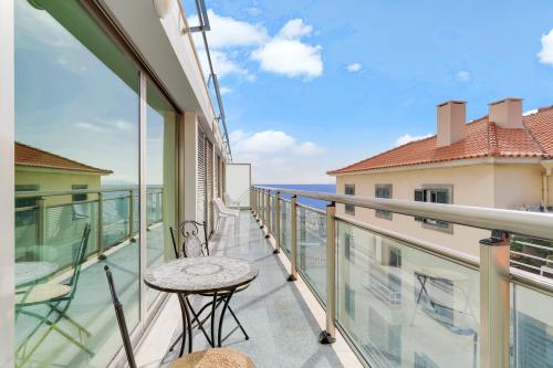 uma varanda com uma mesa e cadeiras e o oceano em Sunny Beach Machico Apartment by HR Madeira em Machico