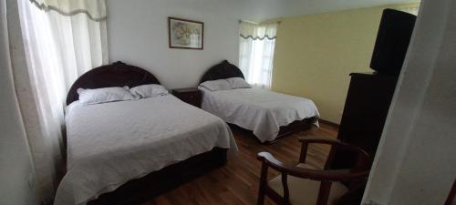 ein Hotelzimmer mit 2 Betten und einem Stuhl in der Unterkunft villa concha in Paipa