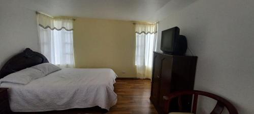 a bedroom with a bed and a flat screen tv at villa concha in Paipa