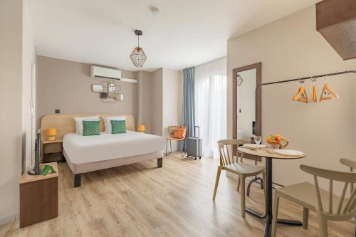 Habitación de hotel con cama, mesa y sillas en Appart'City Classic Toulouse Colomiers en Colomiers