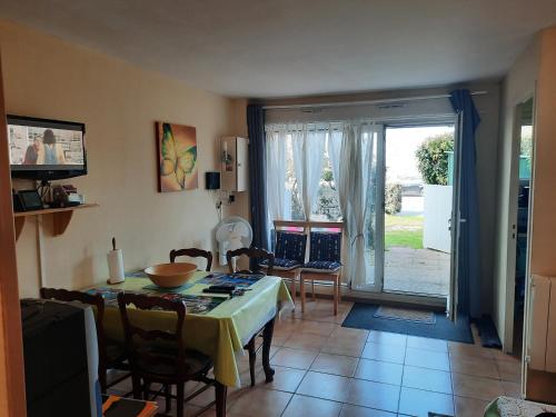 une salle à manger avec une table et des chaises et une fenêtre dans l'établissement FACE ECOLE DE VOILE LA PLAGE A 50 metres, à Bernières-sur-Mer