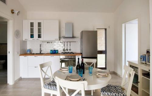 a kitchen with a white table and chairs and a kitchen with white cabinets at La Casa dei Pesci in Budoni